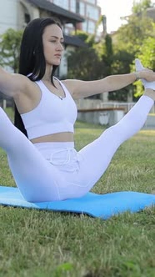 Vertical Video Woman Doing Yoga Doing Exercises Training Alone in Sportswear on Green Area of