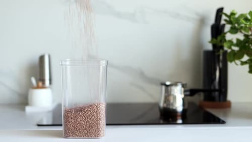 Buckwheat Pouring into a Clear Container in Kitchen