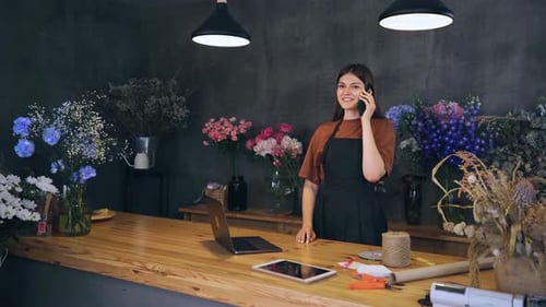 Happy Beautiful Young Woman Owner Florist of a Flower Shop Inspired By a Successful Deal Deal Over