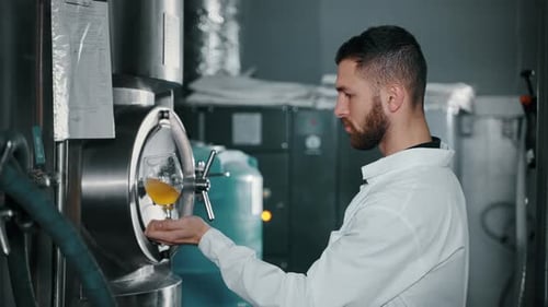 Un brasseur professionnel verse de la bière légère à partir de la cuve de fermentation dans un atelier de brasserie