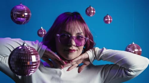 Dancer Woman with Pink Dyed Hair Dancing Spinning Disco Balls on Blue Studio