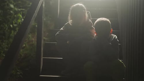 Children Sitting on Wooden Stairs in a Forest