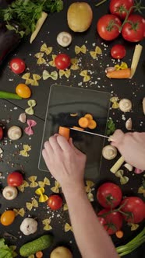Vertical of Crazy Cook Cutting Carrot on Digital Tablet Damaging the Device