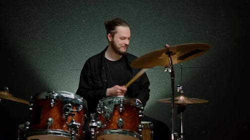 a young male drummer plays a drum kit in a recording studio at a professional musician's rehearsal