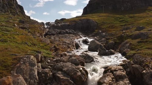 Rocky riverbed and waterfall in Norway’s serene mountain landscape with flowing water