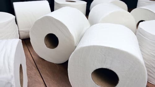 Panning shot of toilet paper rolls on wood surface