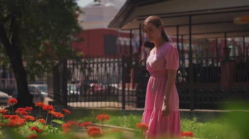 Youthful Woman in Pink Outfit Wanders Through Brightly Lit Garden Setting Young Woman Dressed in