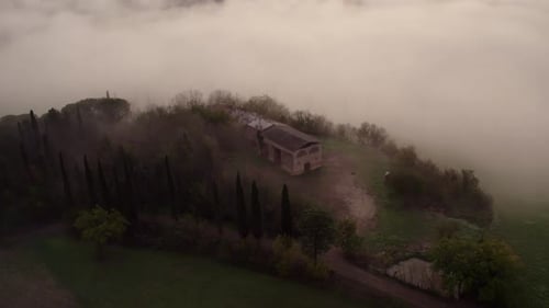 Aerial view of misty morning with villa and cypress trees, Italy.