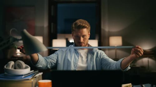 Young Adult Measures Desk with Tape Measure at Night