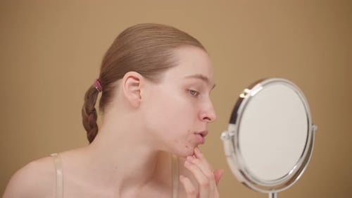 Young Woman Examining Skin Concern In Mirror