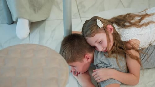 Girl Comforting Boy Lying on Floor