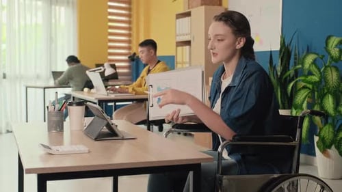 Woman Presenting Data From Wheelchair in Modern Office