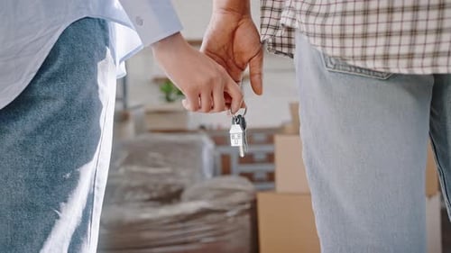 Cropped View of a Couple Holding Hands and Key to New Home Moving in Together