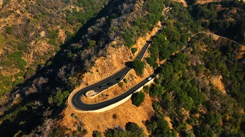 Highway turn on the mountain top. Some cars stand on the road near the slope