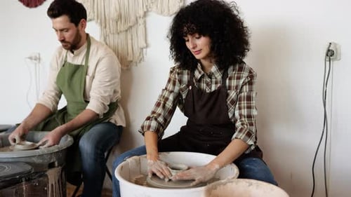 Potiers hommes et femmes travaillant au Potters Wheel Fabriquant un vase en argile