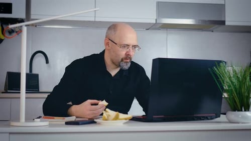Focused Businessman Working on Laptop Computer in Home Office and Eating Pear Due to Lack of Time