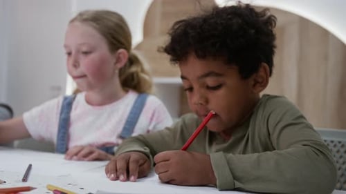 Two Children Drawing with Colored Pencils at Table