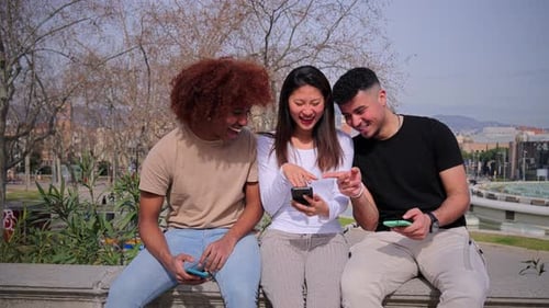 Friends Laughing Together While Looking at Phones