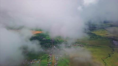 Aerial view of the fluffy clouds at summer sky. Flight over the rural areas with green summer fields