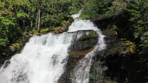 A breathtaking waterfall cascades down rocky cliffs surrounded by lush greenery