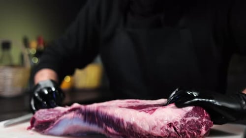 Male Chef Black Gloves Hands Putting Big Meat Steak on Table Slicing Remote Fat Closeup Slow Motion