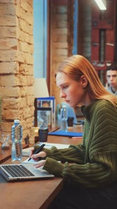 Vertical Screen Focused Woman Working on Laptop in Bustling Coworking Space