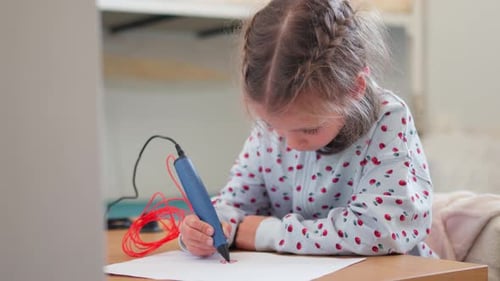 Child Drawing with Three-Dimensional Pen at Desk Indoors