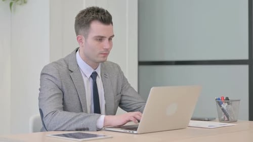 Young Businessman Typing on Laptop in Office