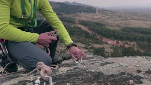 Alpinista fixando uma corda em um mosquetão e prendendo-a antes de subir. Esporte radical.