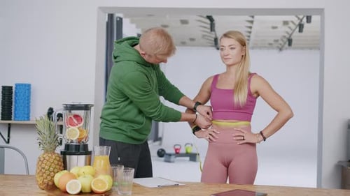 Man Measures Woman's Waist in Bright Modern Setting