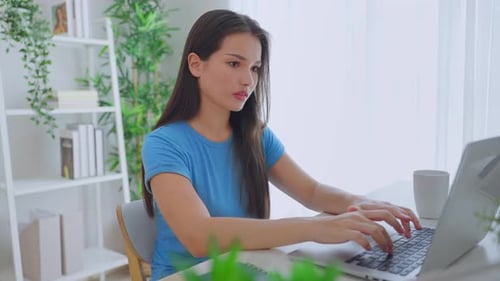 Woman Typing on Laptop at Bright Desk Indoors