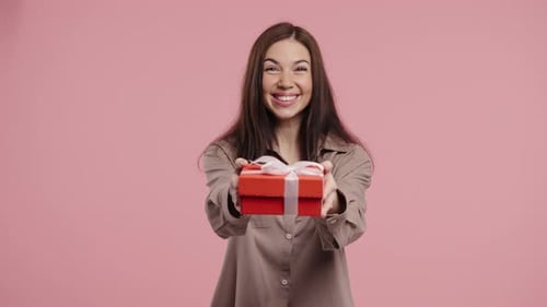 Smiling Woman Presents Red Gift with White Ribbon