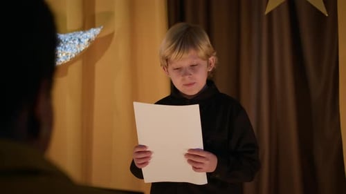 Boy Reading Script During Audition in Theatre
