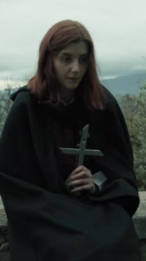 Mujer religiosa ora con un crucifijo en el cementerio entre los árboles