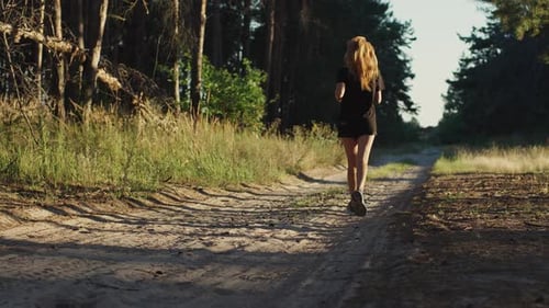Slow motion female jogger in sportswear running in the forest among green trees, concept of fitness