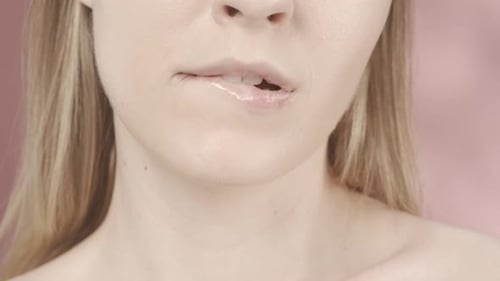 A Seminude Woman Bit Her Lower Lip in a Studio on a Pink Background Seductive Lips of a Woman with a