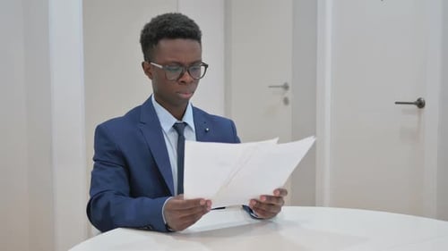African Businessman Reviewing Documents in Office