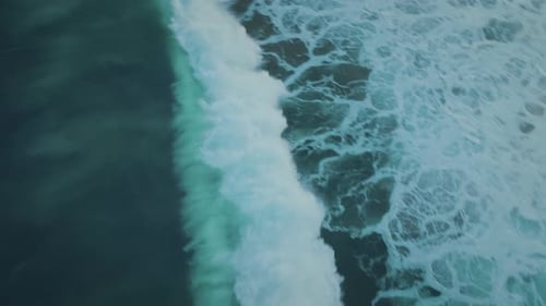 Die tieftürkisblaue Meeresflut bewegt sich in Richtung Küste und erzeugt eine wunderschöne samtige Wasserstruktur.