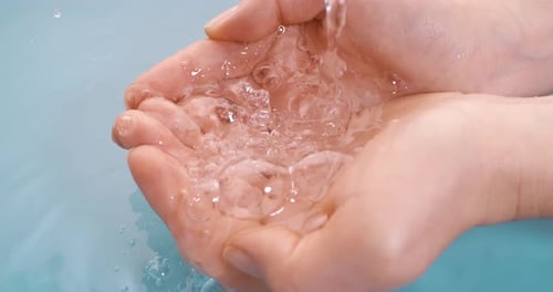 Clean drinking water flows in the palms of the woman hands. Shot on super slow motion camera 1000