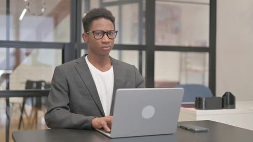 Young Adult Working at Laptop in Modern Office