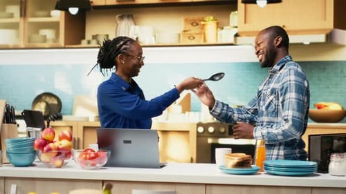 Playful Couple Singing with Kitchen Utensils at Home