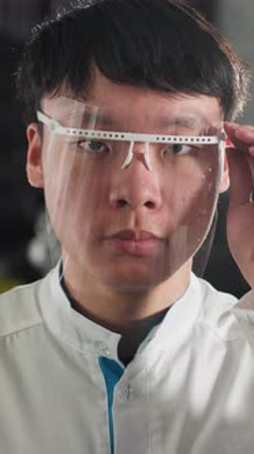 Chemical Engineer Adjusting Protective Glass in Illuminated Workshop