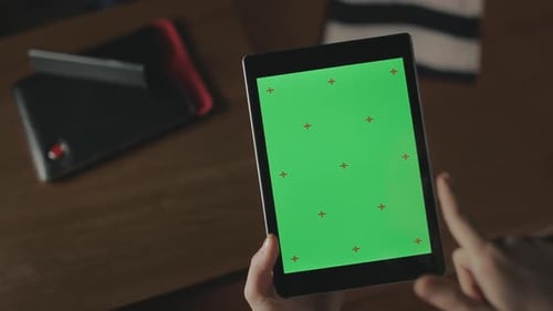 Female Hand Holding Tablet on Wooden Background. Close Up Woman Swiping Tablet