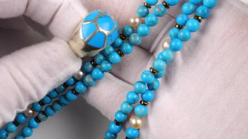 Elegant silver ring with natural turquoise inlay is presented alongside matching blue bead necklace.