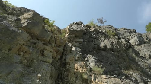 Aerial elevating low angle shot of rock cliff on summer day in Europe