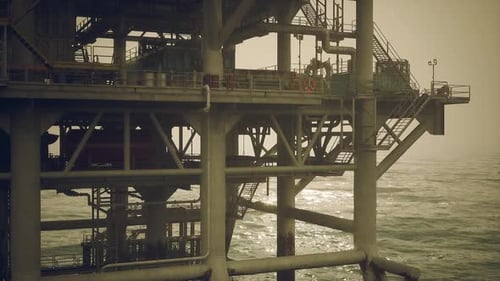Oil Rig Operates Over the Ocean on a Misty Day with Safety Measures in Place