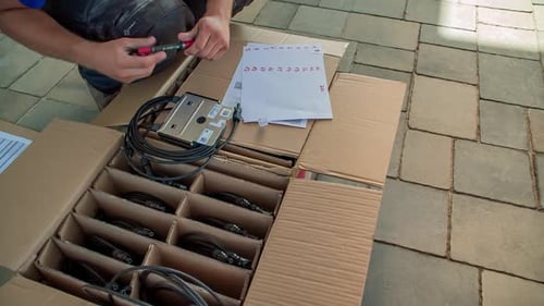 An electrician marking up the electric circuit breakers on paper outdoor.