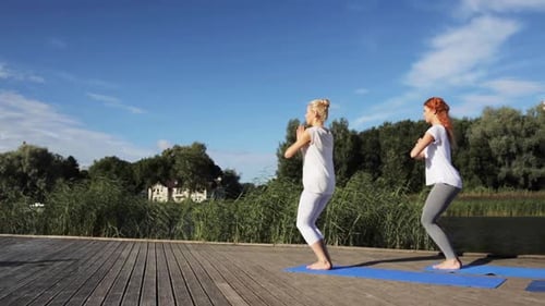 Yoga class practicing chair pose on river berth for fitness and wellbeing