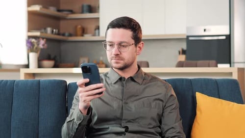 Man Uses Smartphone on Couch in Home