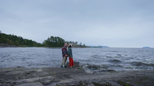 Romantic Loving Couple Standing On Big Stone On Shore Of Beautiful Lake In Autumn Day